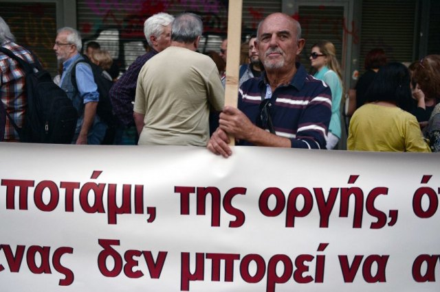 Ein Demonstrant steht hinter einem Anti-Austeritäts-Banner, während Beschäftigte des Öffentlichen Dienstes und Rentner am 21. October in Athen vor dem Arbeitsministerium protestieren. Die Gläubiger Griechenlands konferierten mit dem Finanzminister Euclid Tsakalotos. AFP PHOTO / LOUISA GOULIAMAKI