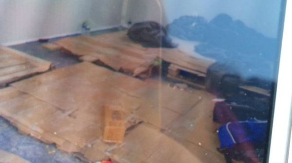 A photo taken by a refugee in the camp, shown to us on a smartphone screen. People are sleeping on pallets which have been covered with cardboard.